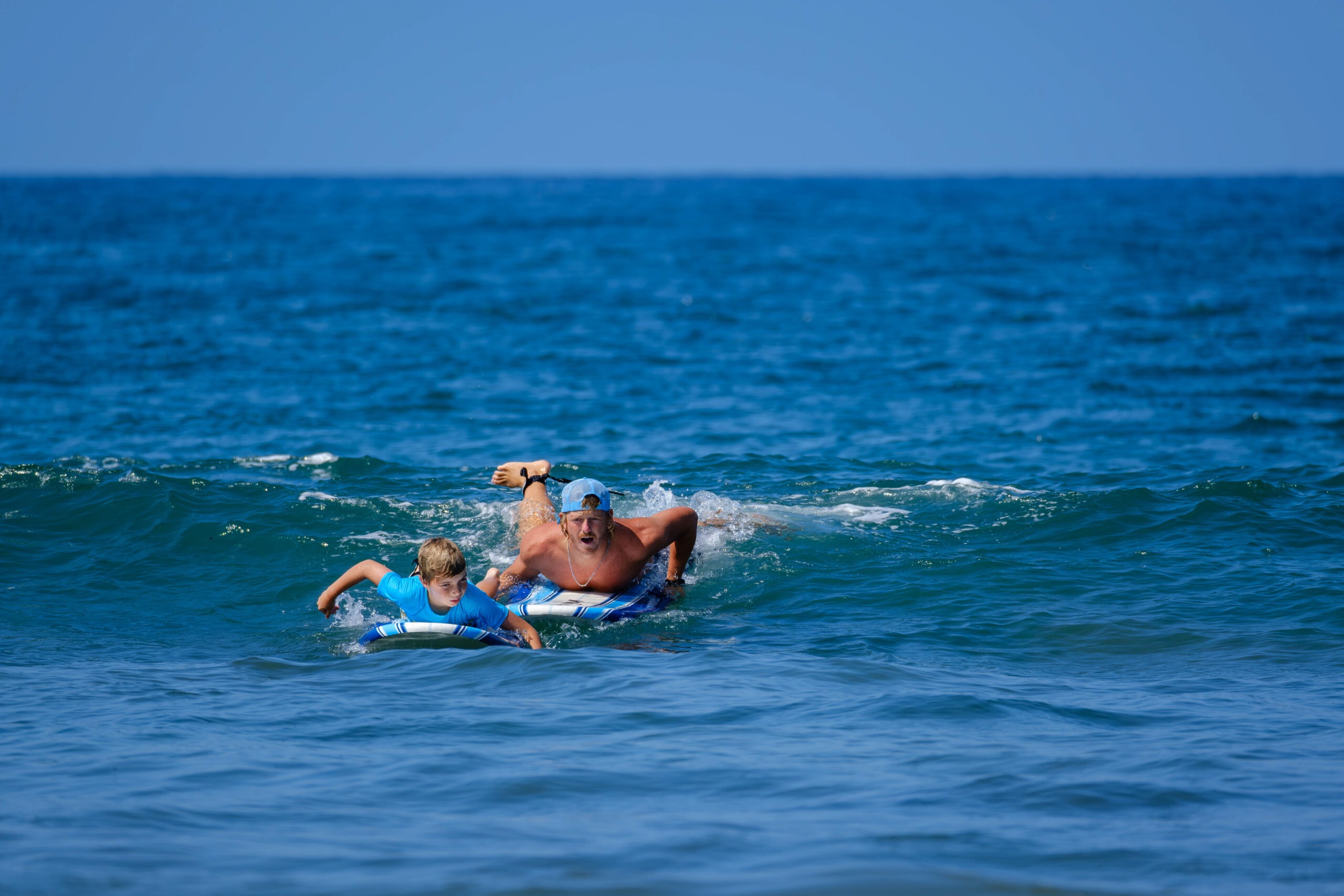 Father and son swimming out on boogie boards through the waves
